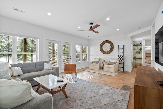 living room with ceiling fan and wood walls