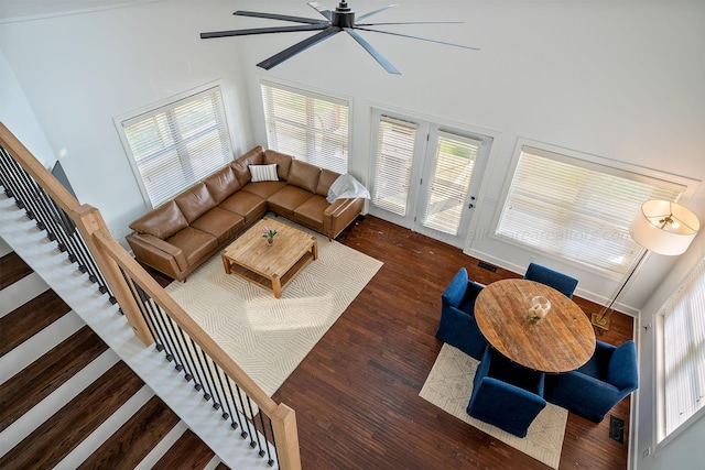 living room featuring dark wood-type flooring, ceiling fan, and a high ceiling