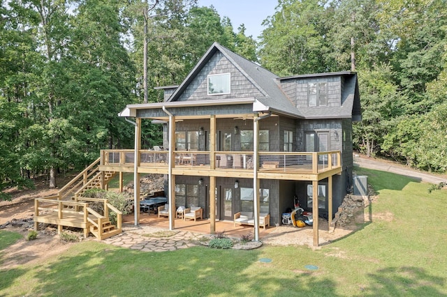 rear view of property featuring a wooden deck, a patio area, and a lawn