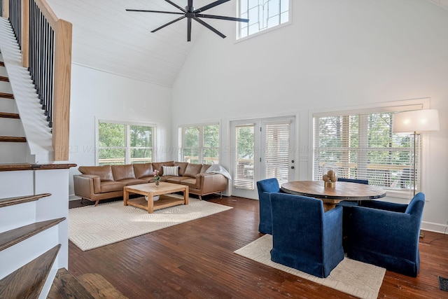 living room with a high ceiling, ceiling fan, plenty of natural light, and dark hardwood / wood-style flooring