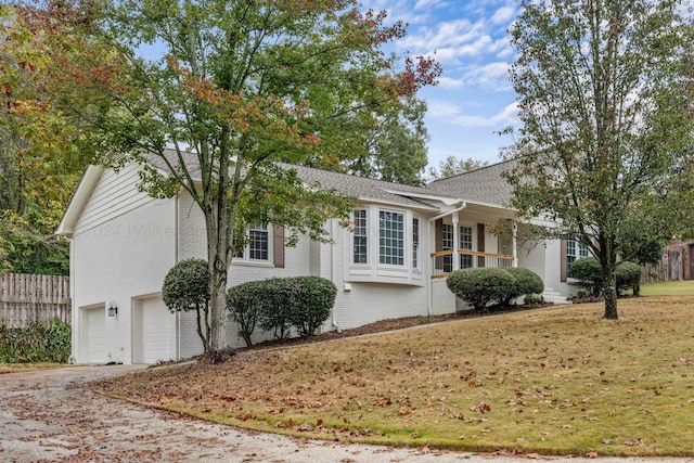 view of front of house featuring covered porch, a garage, and a front yard