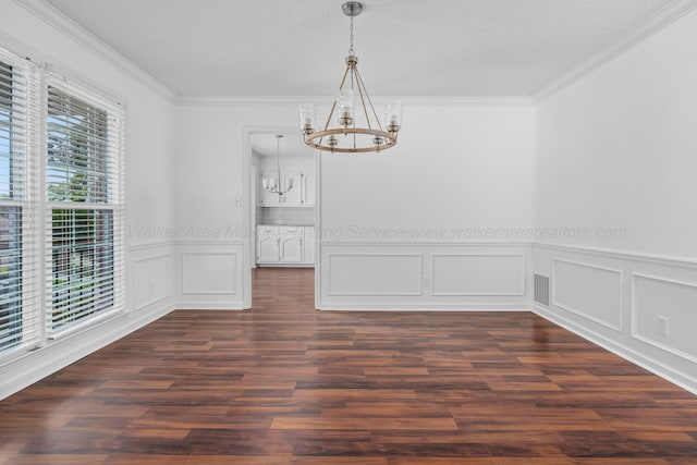 unfurnished dining area with dark hardwood / wood-style floors, crown molding, and a chandelier