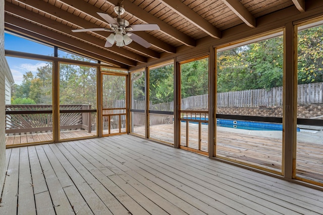 unfurnished sunroom featuring a wealth of natural light, ceiling fan, lofted ceiling with beams, and wooden ceiling