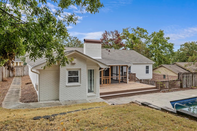 back of property featuring a swimming pool side deck and a lawn