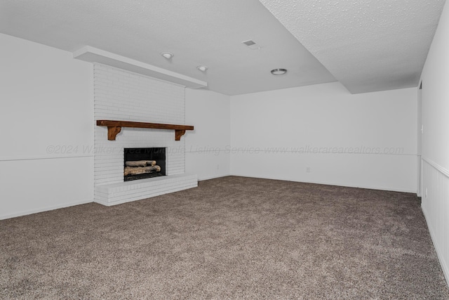 unfurnished living room with dark colored carpet, a textured ceiling, and a fireplace