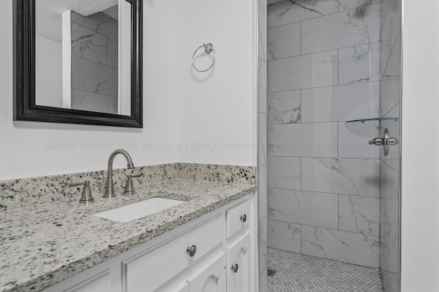 bathroom featuring vanity, a tile shower, and a textured ceiling