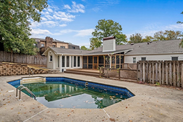 view of pool featuring a wooden deck, a sunroom, and a patio