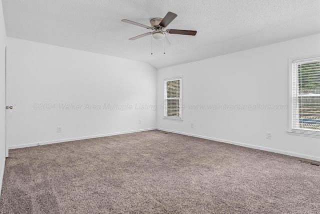 carpeted spare room with lofted ceiling, ceiling fan, and a textured ceiling