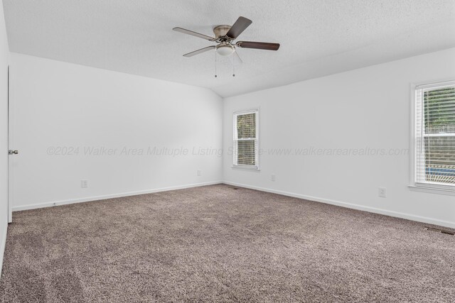 carpeted spare room with lofted ceiling, ceiling fan, and a textured ceiling