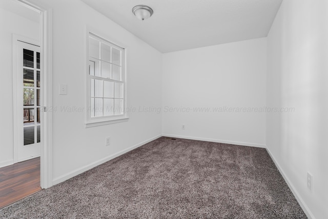 spare room with dark colored carpet