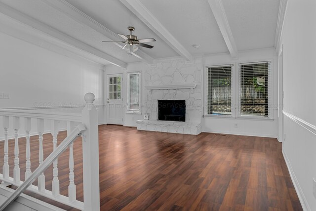 unfurnished living room featuring beam ceiling, hardwood / wood-style flooring, a stone fireplace, and ceiling fan