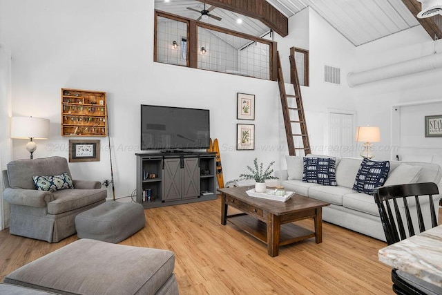 living room featuring ceiling fan, light hardwood / wood-style floors, beamed ceiling, high vaulted ceiling, and wooden ceiling