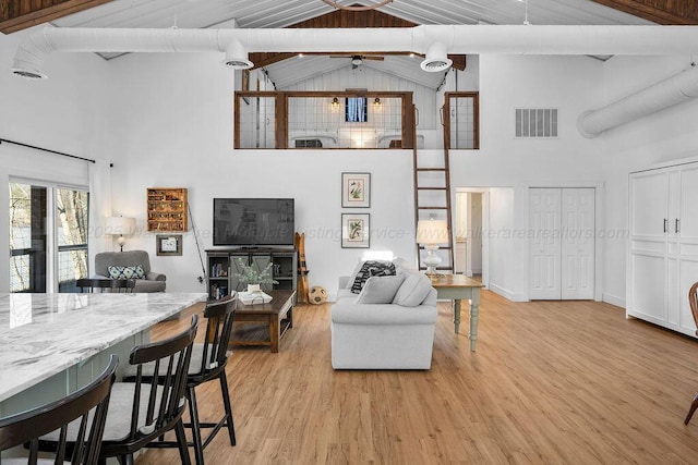 living room featuring ceiling fan, high vaulted ceiling, beam ceiling, and light wood-type flooring