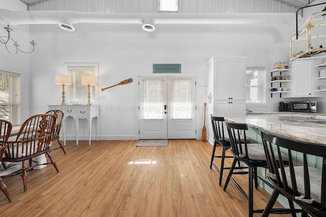 interior space with light stone countertops, a high ceiling, white cabinetry, and light hardwood / wood-style floors