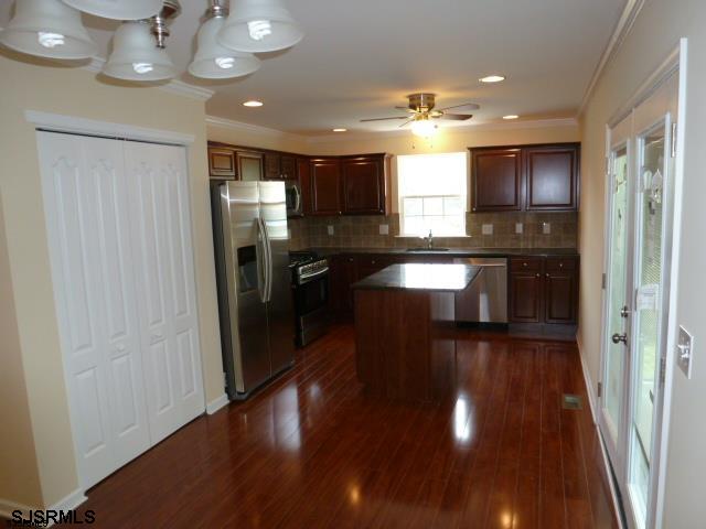 kitchen featuring dark hardwood / wood-style floors, a kitchen island, ceiling fan with notable chandelier, and appliances with stainless steel finishes