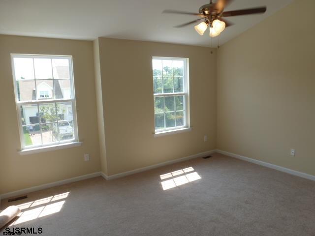 empty room featuring ceiling fan and light colored carpet