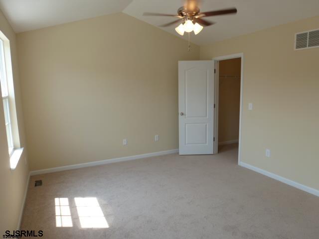 spare room with ceiling fan, light carpet, and vaulted ceiling