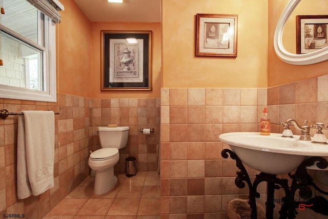 bathroom featuring tile walls, toilet, sink, and tile flooring