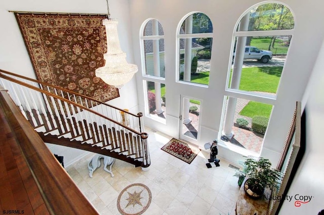 foyer featuring plenty of natural light, light tile floors, and a high ceiling