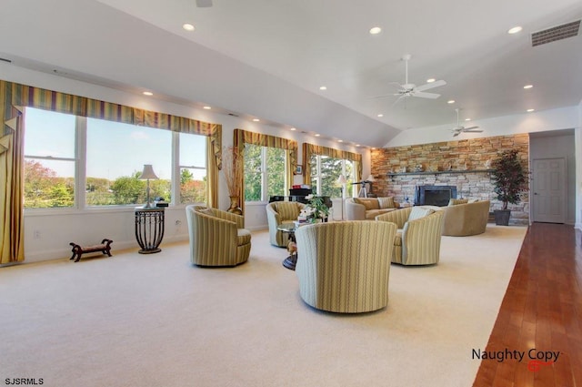 living room with vaulted ceiling, ceiling fan, a stone fireplace, and hardwood / wood-style flooring