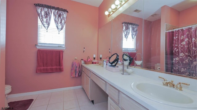 bathroom featuring plenty of natural light, double vanity, tile floors, and toilet