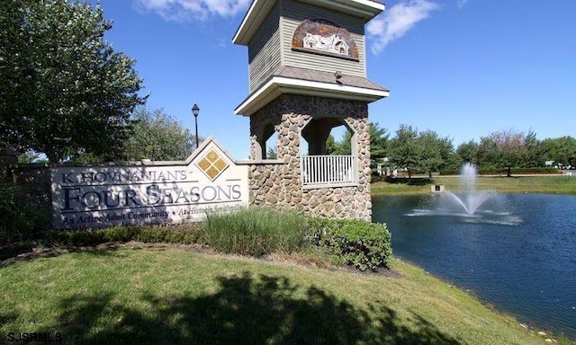 community sign featuring a water view and a yard