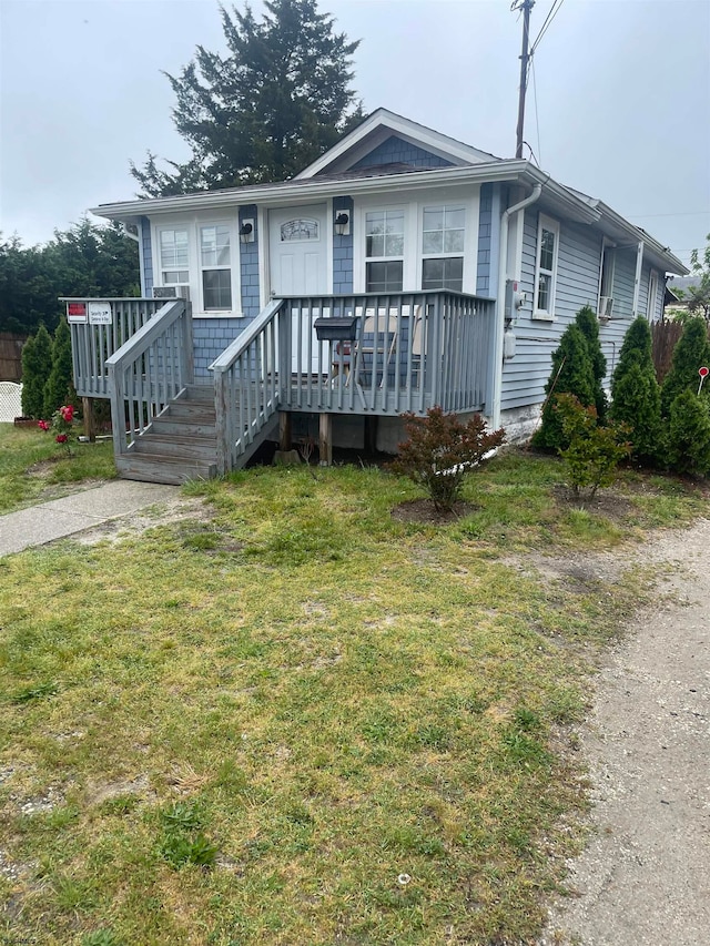 bungalow-style home with a front yard and a deck