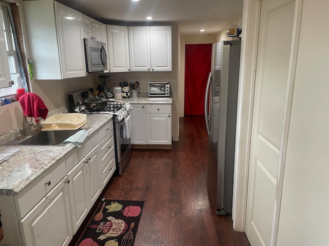 kitchen with white cabinetry, sink, appliances with stainless steel finishes, and dark hardwood / wood-style flooring