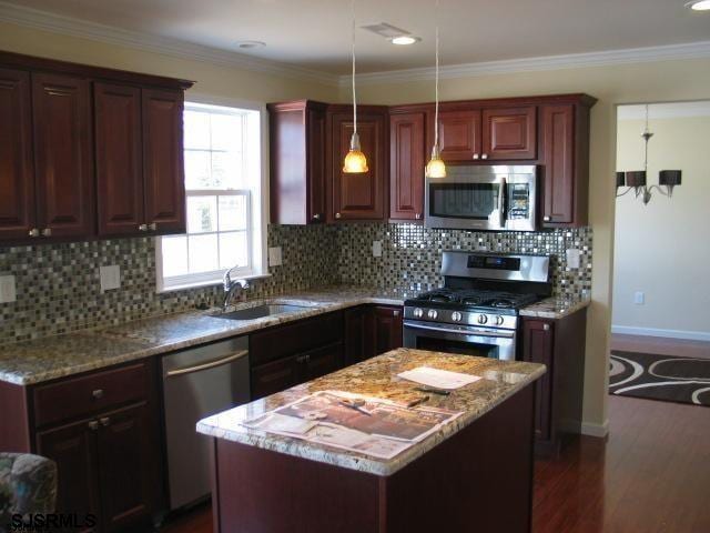 kitchen with dark hardwood / wood-style floors, a kitchen island, appliances with stainless steel finishes, light stone countertops, and tasteful backsplash