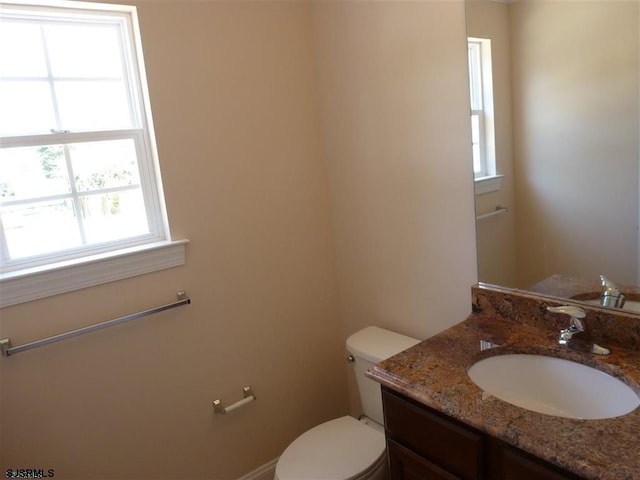 bathroom featuring a wealth of natural light, toilet, and vanity