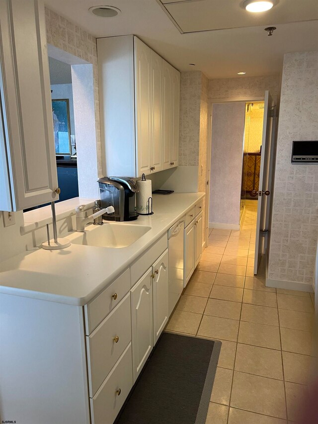 kitchen featuring sink, light tile patterned floors, kitchen peninsula, white dishwasher, and white cabinets