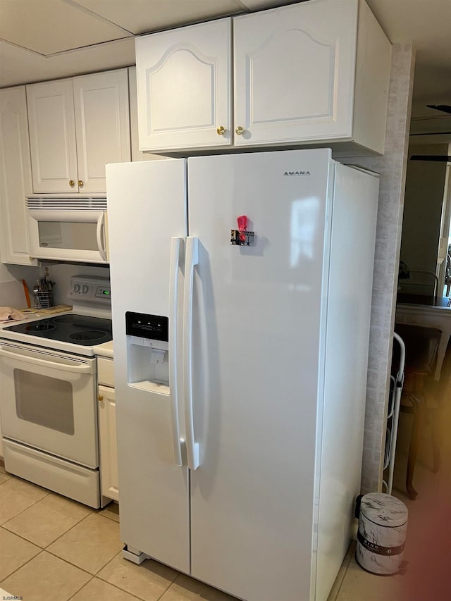 kitchen featuring white cabinets, light tile patterned flooring, and white appliances