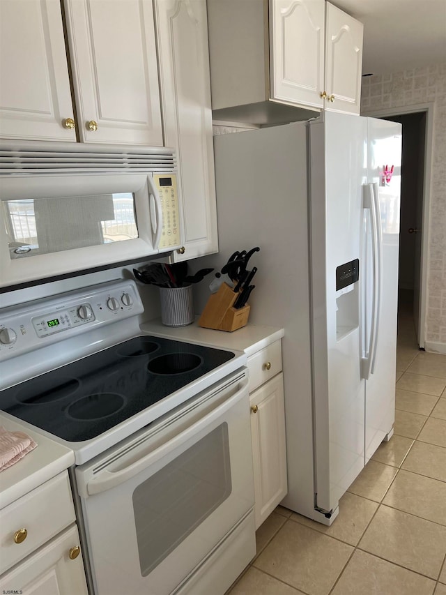 kitchen with white cabinetry, light tile patterned floors, and white appliances