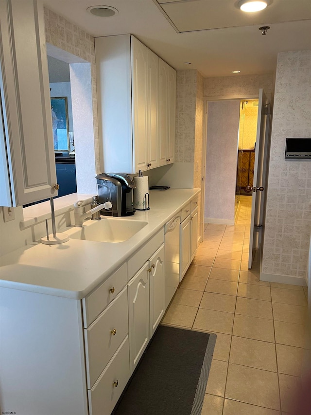 kitchen featuring dishwasher, sink, light tile patterned floors, kitchen peninsula, and white cabinets