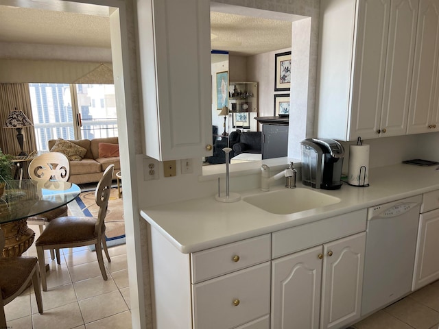 kitchen featuring a textured ceiling, sink, dishwasher, white cabinets, and light tile patterned flooring