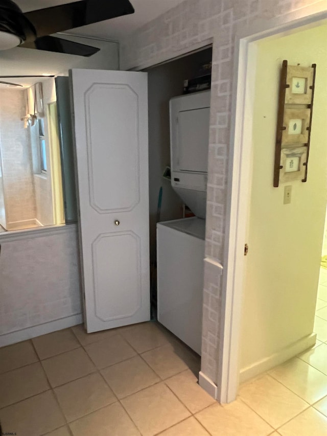 laundry room featuring stacked washing maching and dryer and light tile patterned floors