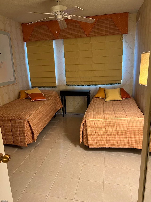 tiled bedroom featuring ceiling fan and a textured ceiling