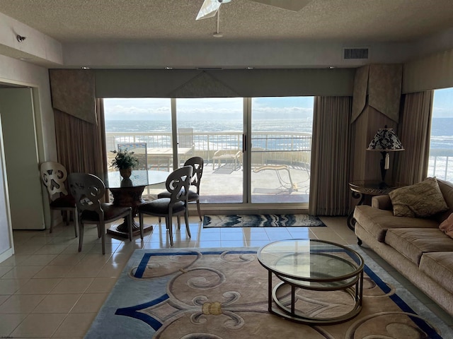 living room with a wealth of natural light, a water view, and light tile patterned floors