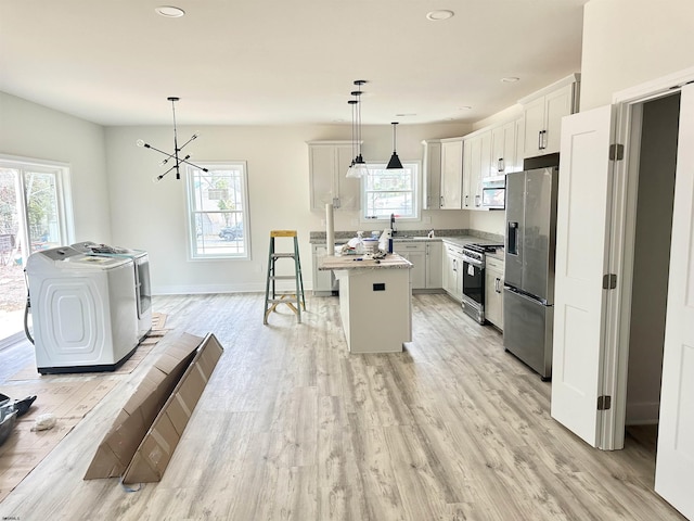 kitchen featuring stainless steel appliances, a wealth of natural light, and washing machine and clothes dryer