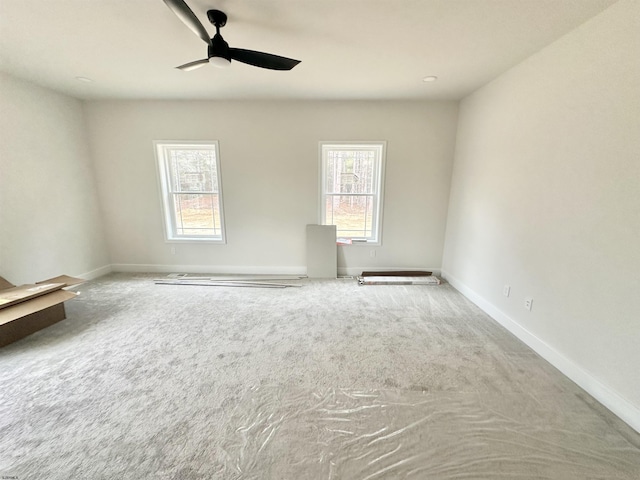 unfurnished room featuring carpet, plenty of natural light, baseboards, and ceiling fan