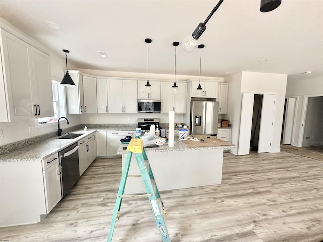 kitchen with stainless steel appliances, light wood-style flooring, white cabinetry, and a center island