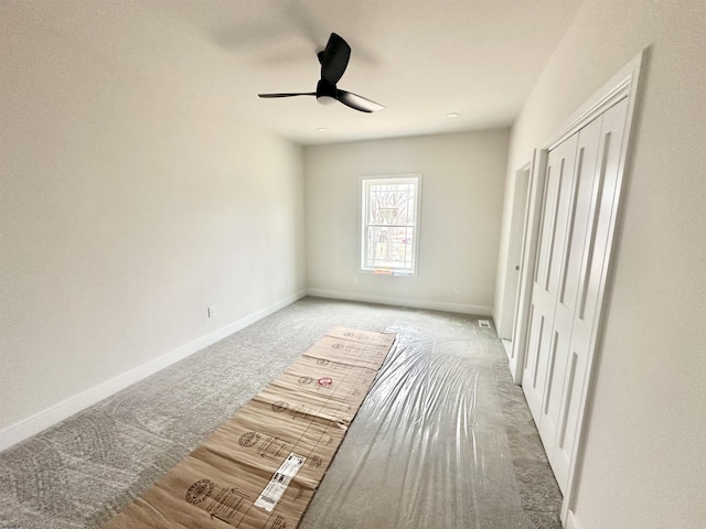 unfurnished bedroom featuring carpet floors, a ceiling fan, baseboards, and a closet