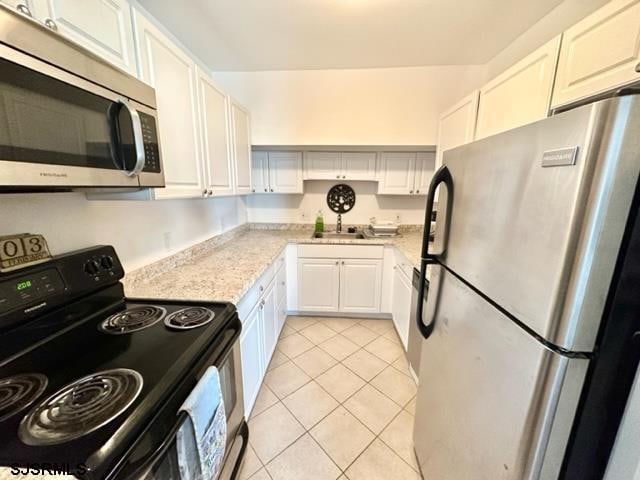 kitchen featuring sink, light tile patterned floors, appliances with stainless steel finishes, and white cabinets