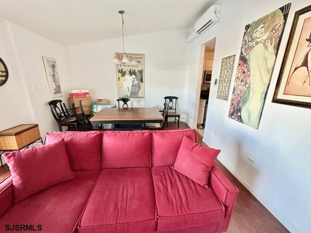 living room with dark wood-type flooring, vaulted ceiling, and a wall unit AC