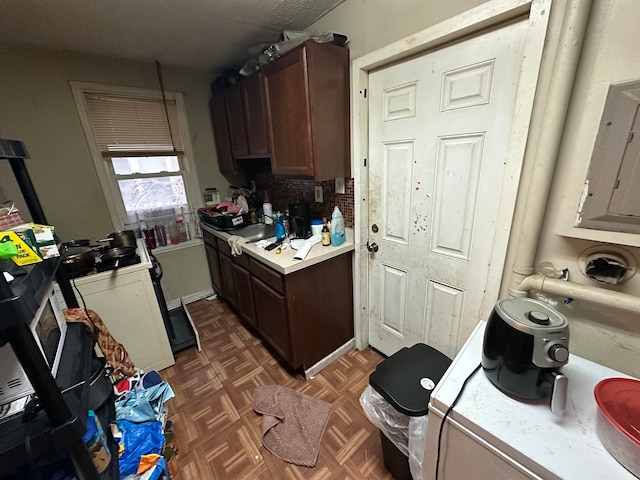 kitchen with backsplash, dark brown cabinetry, and dark parquet flooring