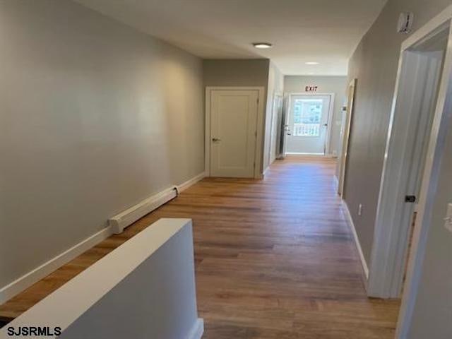 corridor with hardwood / wood-style floors and baseboard heating