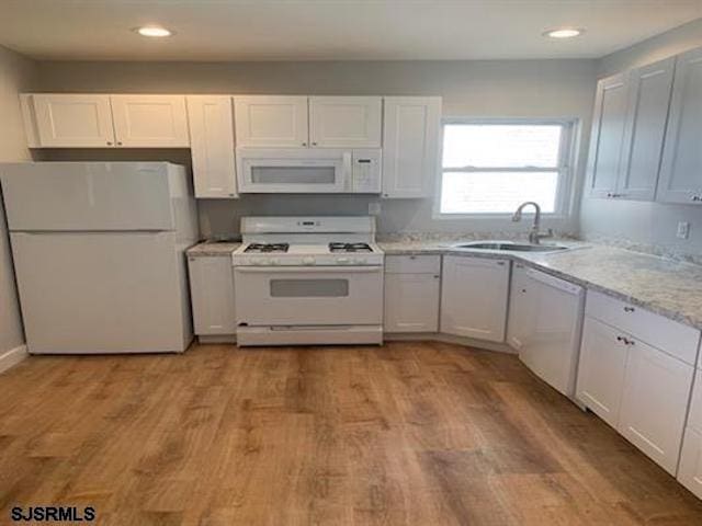 kitchen featuring white cabinets, light hardwood / wood-style floors, and white appliances