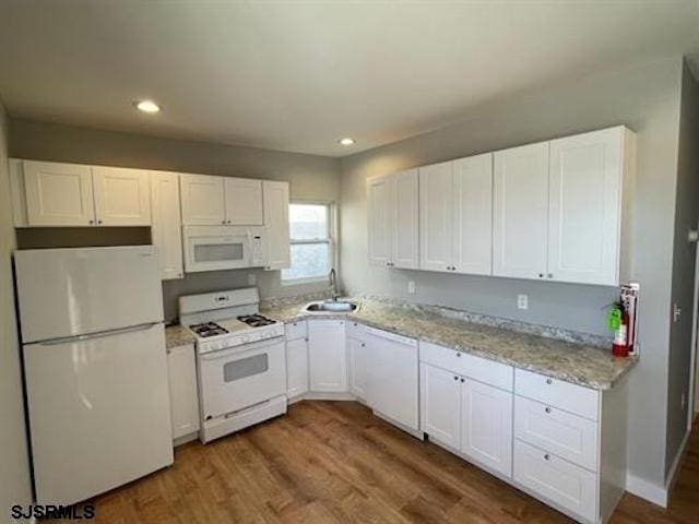 kitchen with hardwood / wood-style flooring, light stone counters, white appliances, and white cabinetry