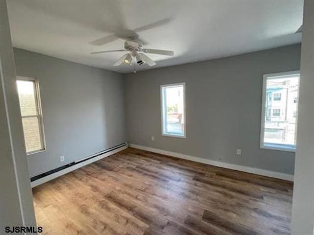 spare room featuring ceiling fan, a baseboard heating unit, and hardwood / wood-style flooring