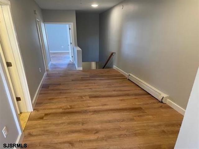 hall featuring a baseboard heating unit and light hardwood / wood-style flooring